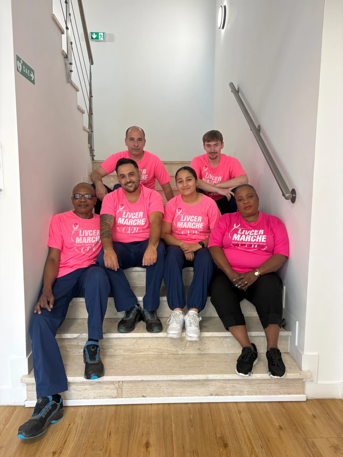 Des collègues en t-shirt rose réunis dans les escaliers de LIVCER.